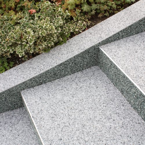 Mit Natursteinteppich belegter seitlicher Stufenabschluss inkl. der Mauerkrone.