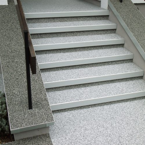 Die Platten auf den Auftrittsflächen der Stufen wurden mit Steinteppich überarbeitet. Als Abschluss wurden wie auf den Mauerkronen ein Terrassenabschlusswinkel verwendet.