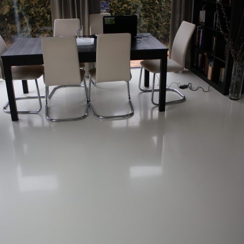 Ein Wohnzimmer mit großen Fensterflächen mit einer Lichtbesändigen lichtgrauen Bodenbeschichtung aus einem 2-K Polyurethanharz.