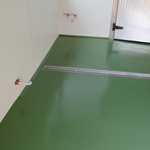 Eine leicht rutschfeste, grüne Bodenbeschichtung mit Eurokeilen als Wandanschluss und einem eingebauten Rigol