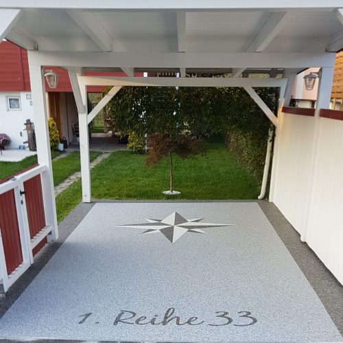 Garagenzufahrt mit Natursteinteppich und der Hausnummer samt Stern mit Steinteppich gestaltet